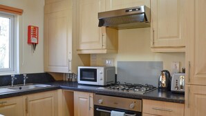 Une cuisine avec des meubles de rangement en bois, un four à micro-ondes, une cuisinière et un grille-pain.