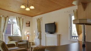 Un salon chaleureux avec une télévision, un plafond en bois et une cheminée.