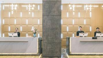 A hotel reception area with marble flooring, two reception desks, and modern lighting fixtures.