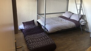 Een stapelbed met beddengoed met een patroon, een houten vloer en een witte muur.