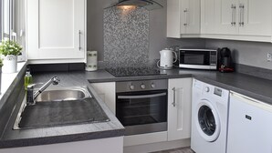 Een moderne keuken met een spoelbak, fornuis, magnetron en wasmachine.