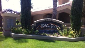 A sign for Bella Terra Condominium with a well-maintained lawn and palm trees. - Resort Style Living in Prime Scottsdale Location (Scottsdale)