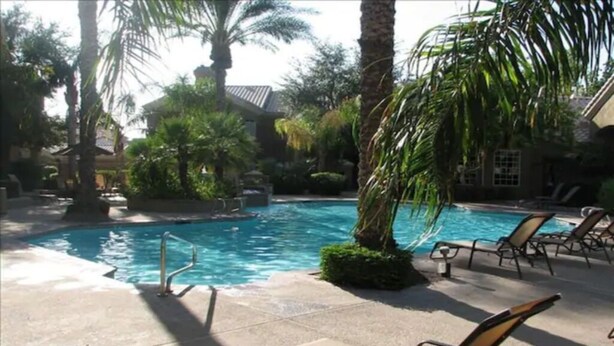 A pool area with lounge chairs and palm trees. - Resort Style Living in Prime Scottsdale Location (Scottsdale)