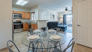 A modern kitchen with built-in appliances, a dining area with a glass table, and a living room with a sofa and a ceiling fan. - Resort Style Living in Prime Scottsdale Location (Scottsdale)
