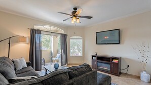 A living room with a sofa, TV, fireplace, and a ceiling fan. - Resort Style Living in Prime Scottsdale Location (Scottsdale)
