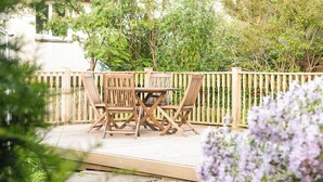 An outdoor wooden deck with a table and chairs, surrounded by a wooden fence and lush greenery. - 3 bedroom accommodation in Dunblane (Dunblane)