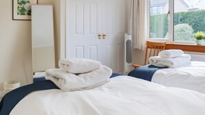 A hotel room with two beds, a window with curtains, a desk with a chair, and a radiator. - 3 bedroom accommodation in Dunblane (Dunblane)