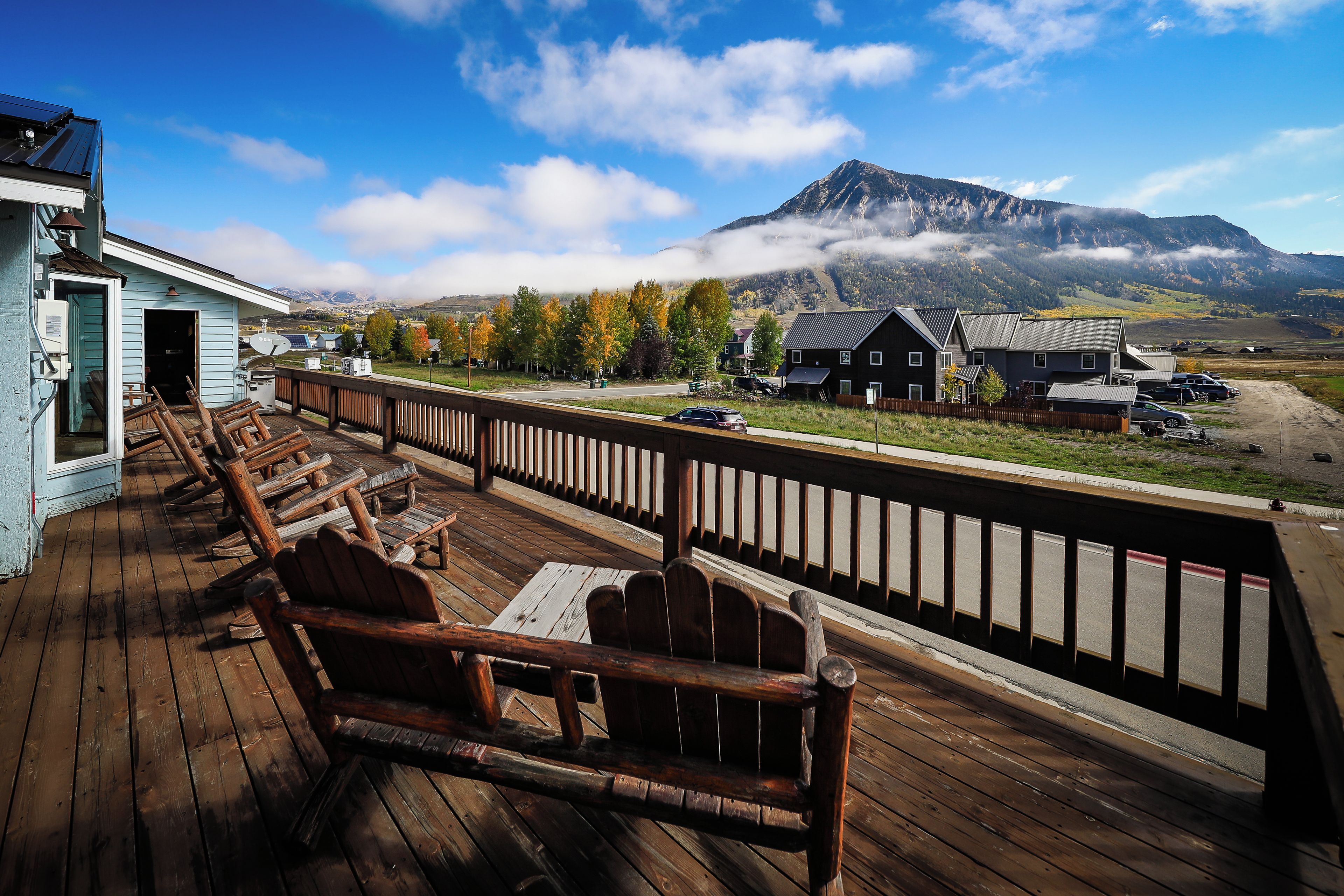 A wooden deck with outdoor seating and a view of a mountain range.