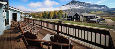 A wooden deck with outdoor seating and a view of a mountain range.