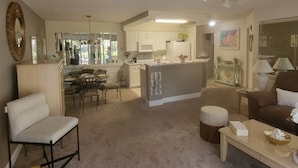 A living room with a sofa, a coffee table, and a dining area with chairs and a table.
