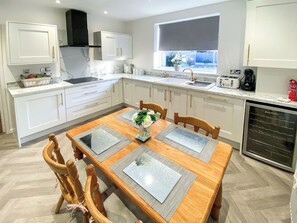 Una cocina moderna con armarios blancos, una mesa de comedor de madera y un lavavajillas empotrado.