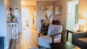 A spacious living room with a sofa, armchair, and coffee table. A dining area with a table and chairs is visible in the background. - Hillside Hideout - Great for groups! - Great Views (Branson)
