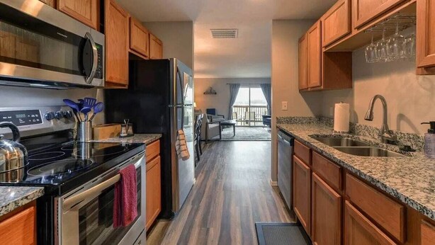 A modern kitchen with wooden cabinets, stainless steel appliances, granite countertops, and a view to a balcony. - Hillside Hideout - Great for groups! - Great Views (Branson)