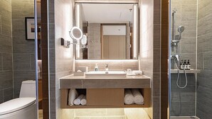 Et moderne badeværelse med et stort spejl, en vask, toilet og bruser.