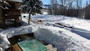 A wooden deck with a hot tub surrounded by snow. - Best Deal, small 2 bedroom unit (Ketchum)
