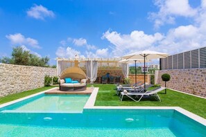 Une piscine avec des chaises longues et un espace de repos abrité.