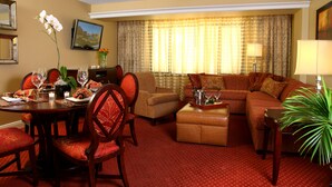 A hotel room with a dining area, a sofa, and a TV.