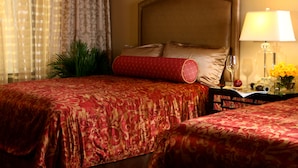 A hotel room with two beds, a nightstand with a lamp, and a window with curtains.