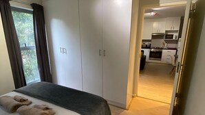 A bedroom with a bed, a wardrobe, and a view of a kitchen. - Tana’s Crib Modern Secure 1 bed apartment (Cape Town)