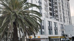 A modern multi-story building with balconies and a sign that reads "The Beach." - Tana’s Crib Modern Secure 1 bed apartment (Cape Town)