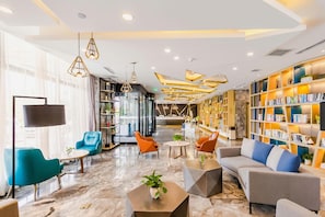 Un hall d’entrée moderne avec des espaces de détente, un comptoir d’accueil et une bibliothèque.