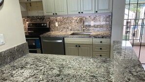 A kitchen with granite countertops, a dishwasher, an oven, and a sink. - Direct Oceanfront, unobstructed ocean view top floor penthouse quiet & private.  (Lahaina)
