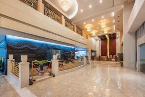 A hotel lobby with a reception desk, a large chandelier, and a high ceiling. - Guangcheng Hotel (Pingliang)