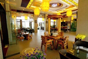 A hotel lobby with a central seating area, multiple dining tables, and a decorative ceiling. - Guangcheng Hotel (Pingliang)