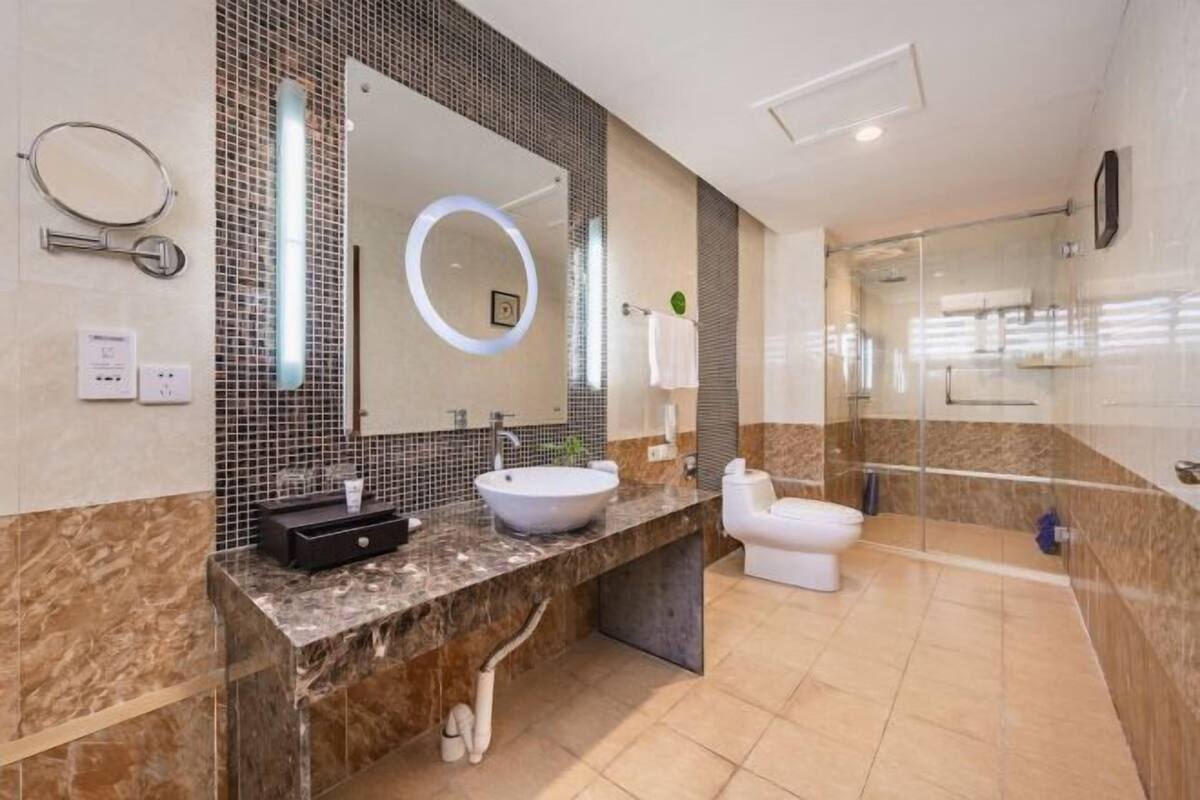 Un baño moderno con un espejo grande, un lavamanos y un inodoro.