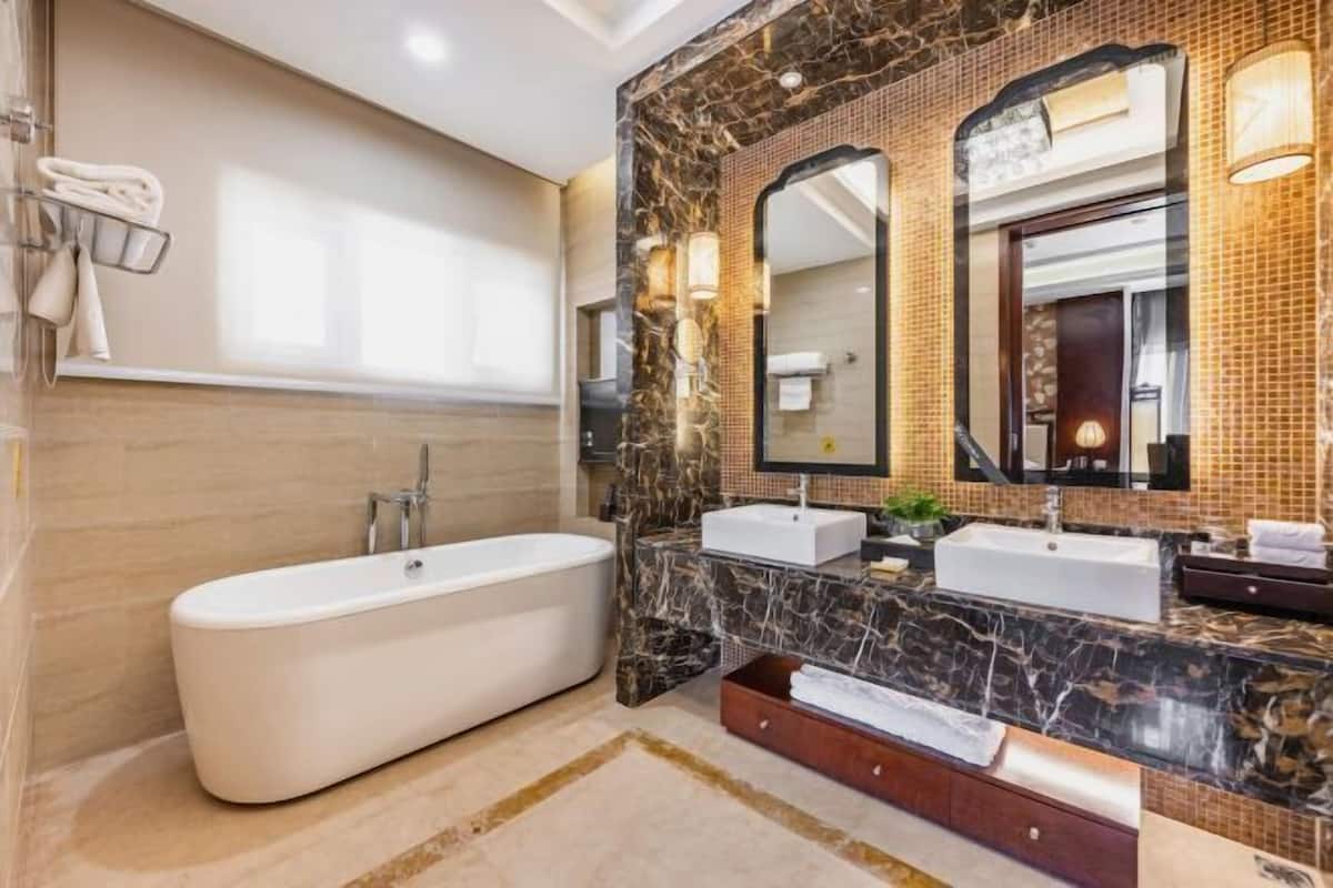 Un baño moderno con una bañera independiente, dos lavamanos y un espejo grande.
