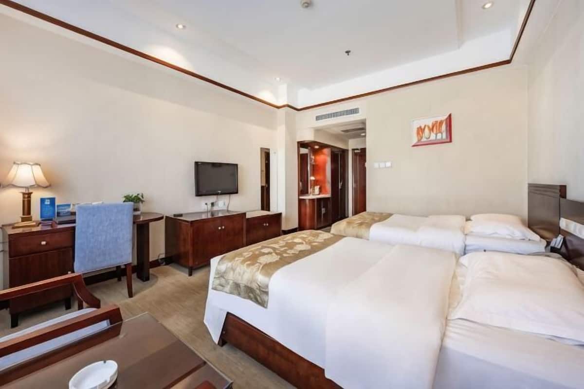 Una habitación de hotel con una cama grande, un escritorio con lámpara, un televisor y un armario.