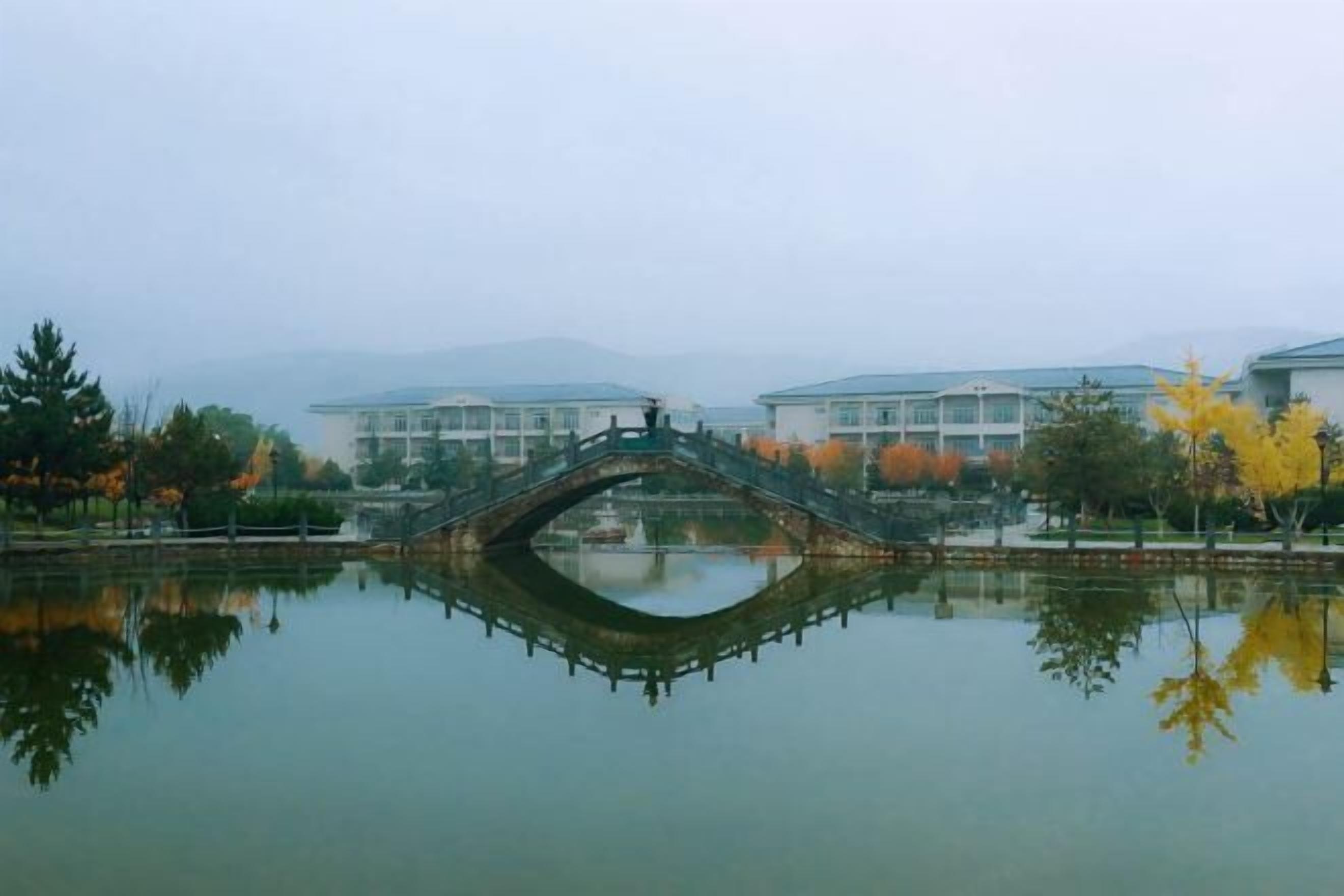 Un lago tranquillo con un ponte di pietra, circondato da edifici in stile architettonico uniforme.