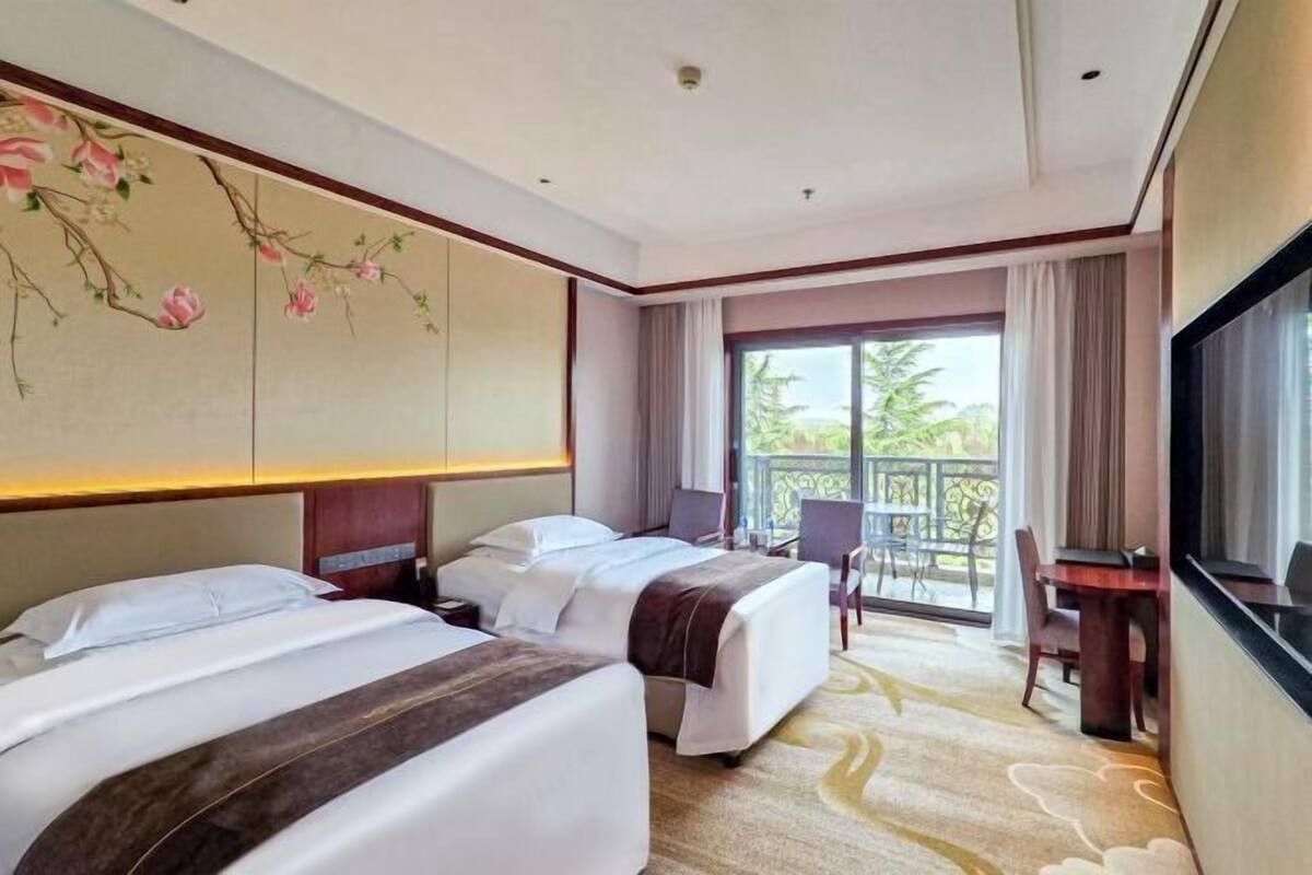 Una habitación de hotel con dos camas, un escritorio y un balcón con vistas.