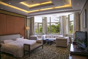 A hotel room with a bed, a sofa, a TV, and large windows with curtains. - Guangcheng Hotel (Pingliang)