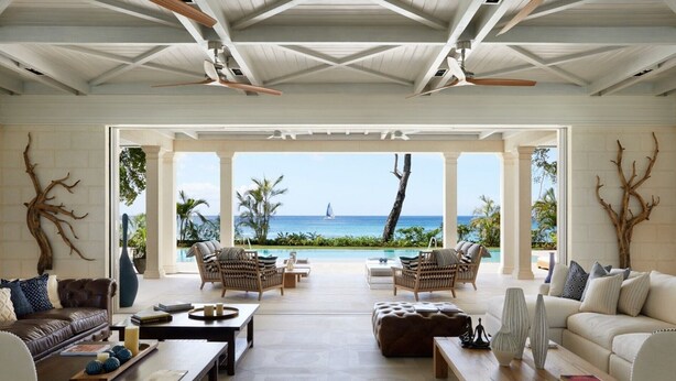 A spacious living room with a view of the ocean, furnished with sofas, chairs, and a coffee table.