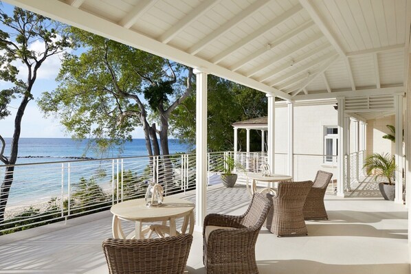 A covered outdoor area with wicker furniture and a view of the sea.