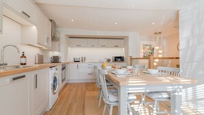 Une cuisine moderne avec un coin repas, des appareils électroménagers intégrés et un lave-linge.