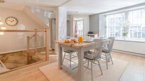 Un espace repas moderne avec une table et des chaises en bois, un coin pour prendre le petit-déjeuner et une vue sur la ville grâce à de grandes fenêtres.