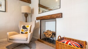 Une pièce chaleureuse avec un fauteuil, une lampe, un miroir, une cheminée et un panier en osier.