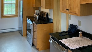 Eine Küche mit Holzausstattung, einem Kühlschrank, einem Backofen und einem Geschirrspüler.