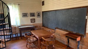 Ein Klassenzimmer mit Holzmöbeln, einer Tafel mit Schrift und einer Treppe.