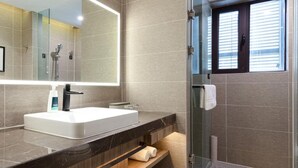 Een moderne badkamer met een grote spiegel, een wit wastafelmeubel, een douche en een toilet.