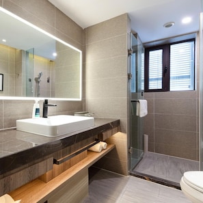Un baño moderno con un espejo grande, un lavamanos blanco, una zona de ducha y un inodoro.