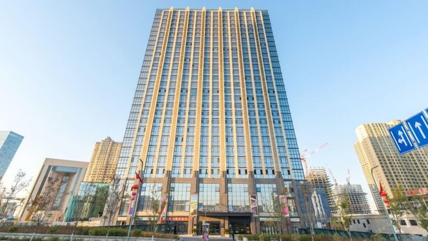 Een hoog, modern hotelgebouw met een glazen gevel en een opvallende ingang.