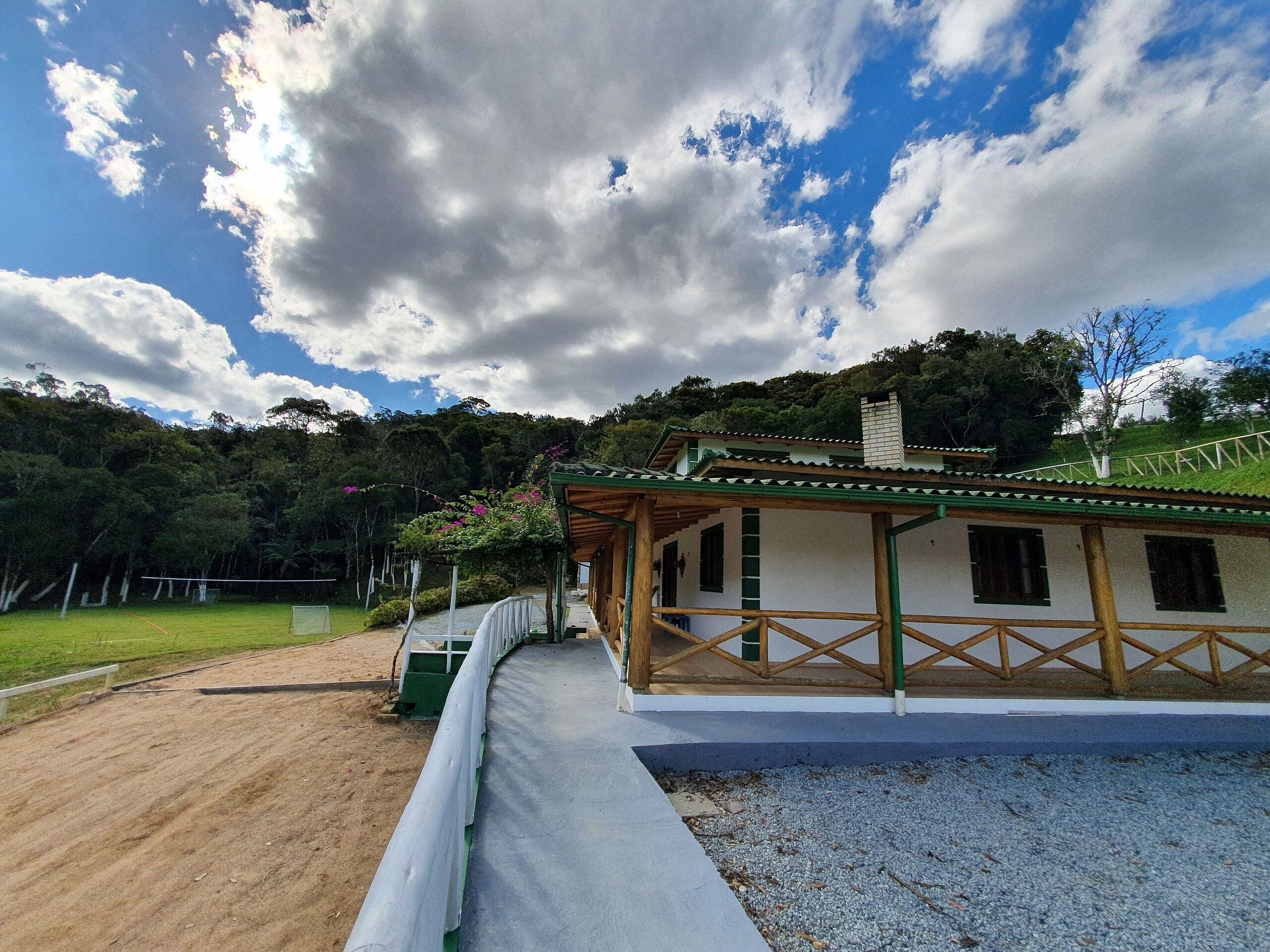 A traditional wooden building with a green roof, surrounded by a gravel path and a grassy area.