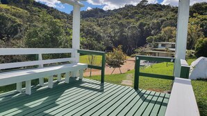 A wooden deck with a bench, surrounded by lush greenery and a mountainous backdrop. - Sítio Pedacinho do Céu na Serra de SC (Aguas Mornas)