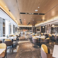Un interior de restaurante moderno con suelo de mármol, techo de madera e iluminación colgante.
