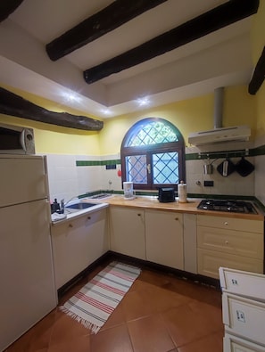 A kitchen with a tiled backsplash, a stove, a refrigerator, and a window with a view. - Swimming pool, wellness and relax in the hills of Bologna (Valsamoggia)