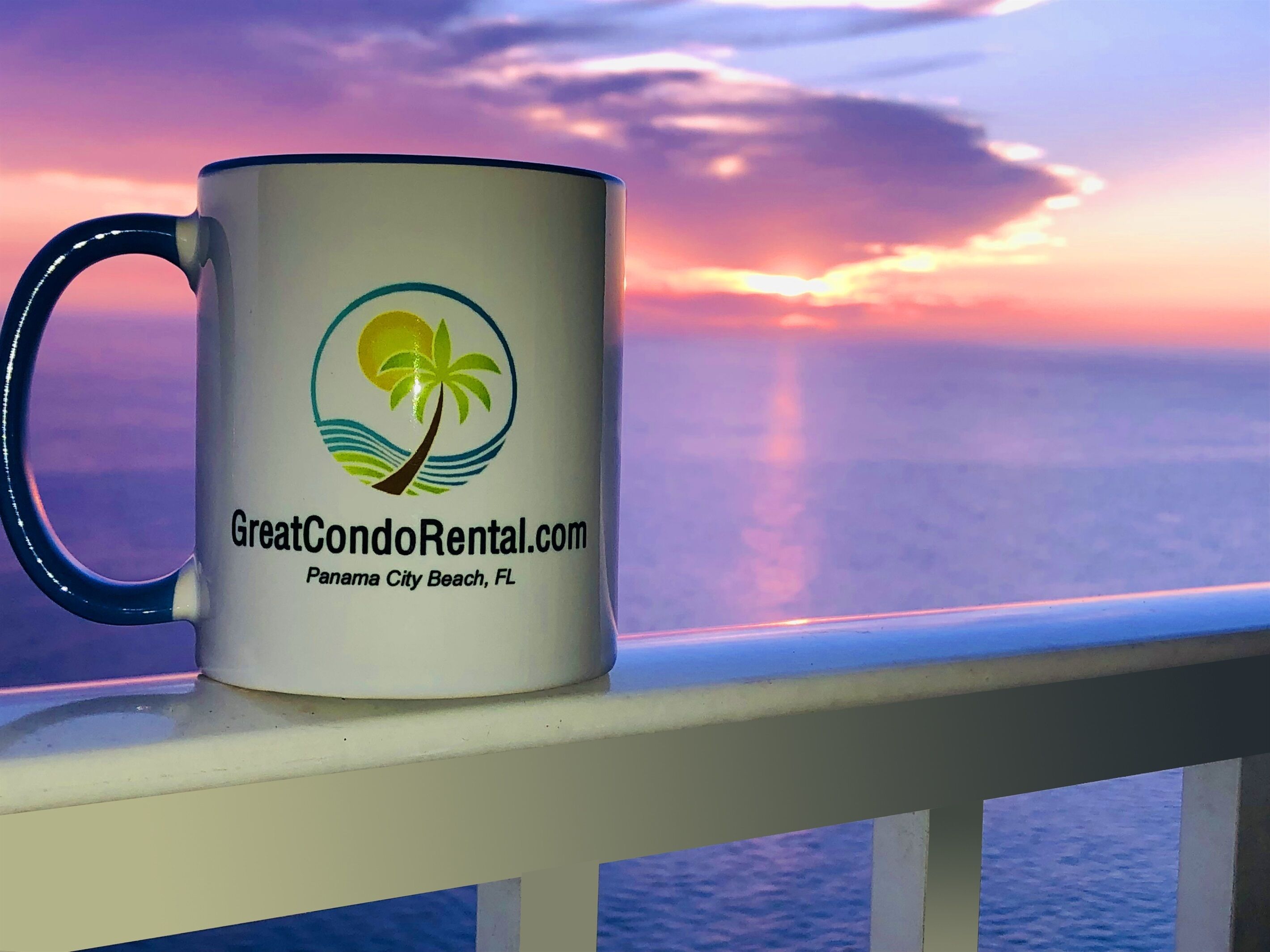 Una taza con un logotipo y texto en un balcón con vista a la puesta de sol.