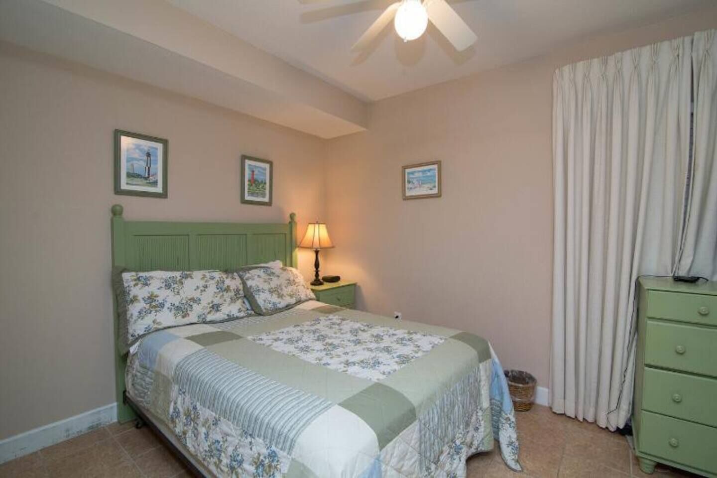 Un dormitorio con cama, mesita de noche, lámpara, cómoda y ventilador de techo.